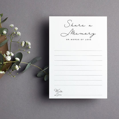 cardamonoly share a memory cards on grey desk with olive foliage, small white flowers and kraft envelope