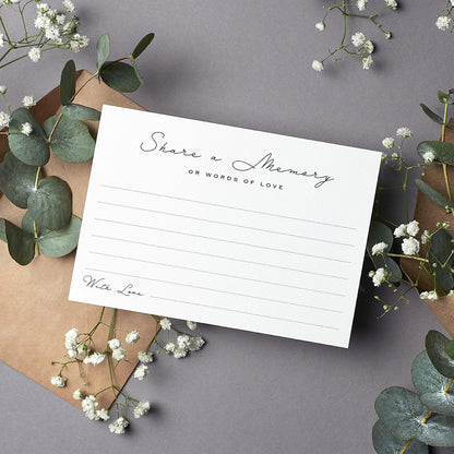 cardamonoly share a memory cards on grey desk with olive foliage, small white flowers and kraft envelope